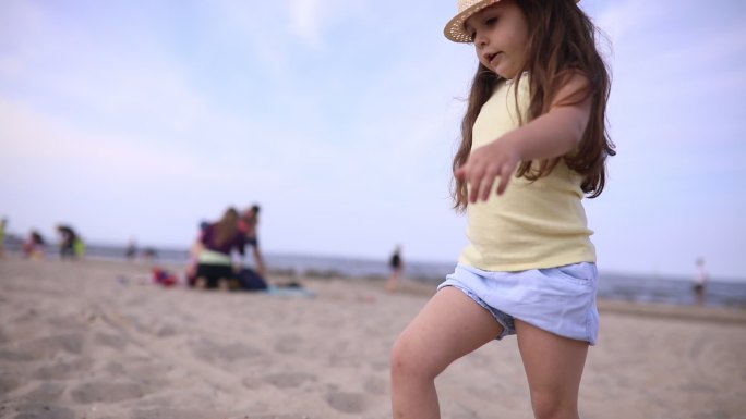 戴帽子的可爱小孩在沙滩上散步
