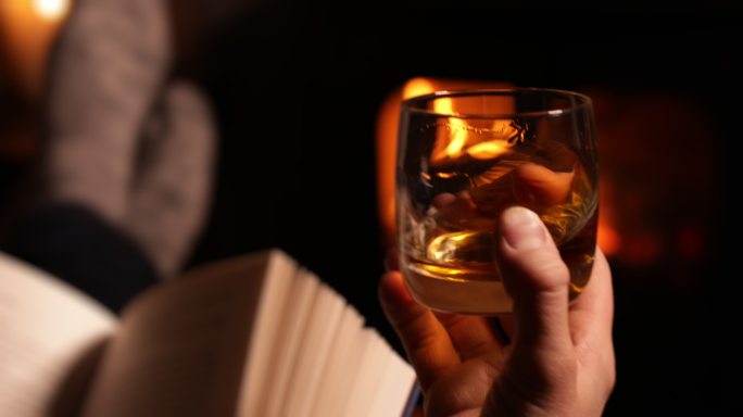 一个人看书，喝着一杯威士忌