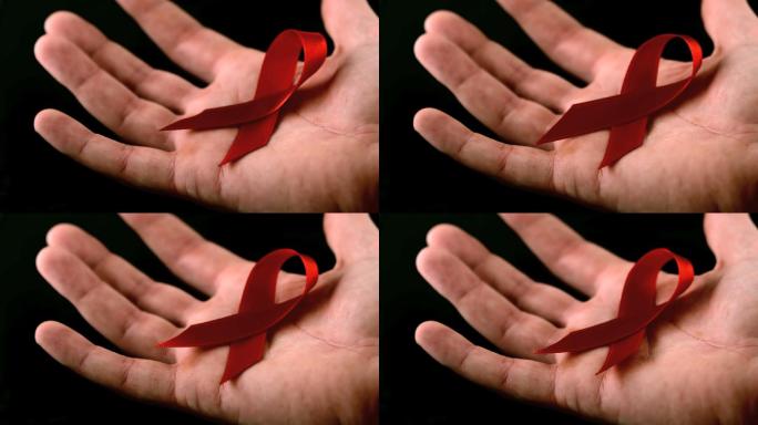 艾滋病红丝带符号落在男人的手上