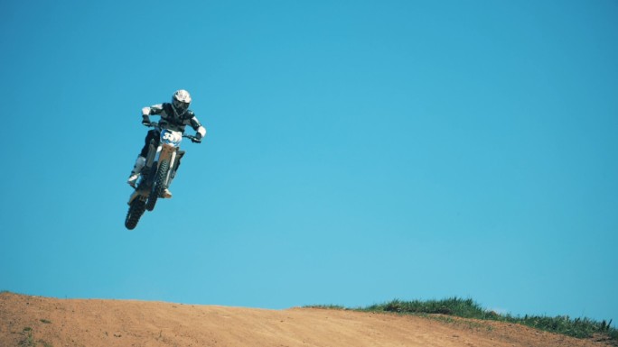 一个骑摩托车的人跨过尘土飞扬的地形