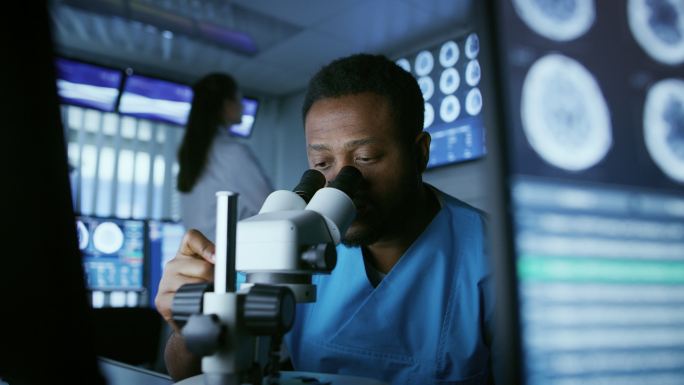 医学研究科学家在实验室的显微镜下观察。