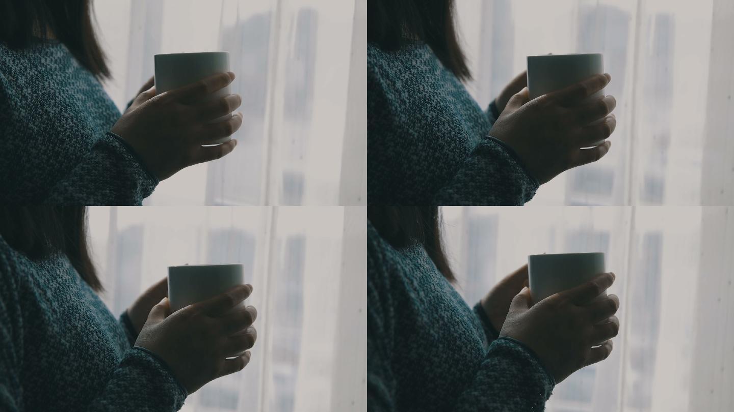 靠近窗户端着咖啡的女人的特写镜头