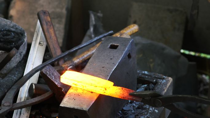 在锻造厂工作的刀匠把烧红的钢锤成形状