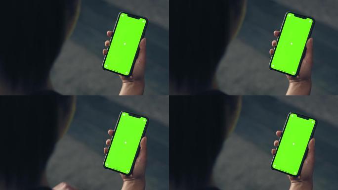 女士在家使用绿屏智能手机的后视图