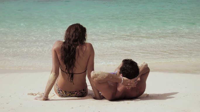 一对年轻夫妇在热带海滩上放松