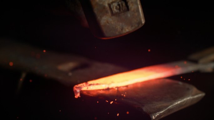 金属工人把一块热金属锻造成刀片。