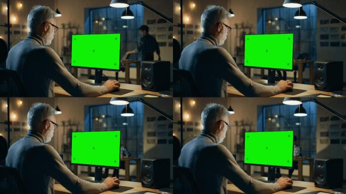 设计师使用带有绿色模拟屏幕的台式电脑。