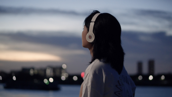傍晚女孩在江边戴着耳机听歌4k视频素材