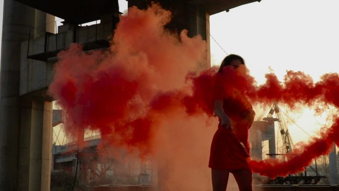 一个穿着红衣服的年轻女子在释放红烟跳舞