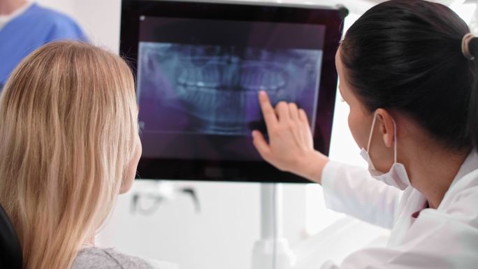 女牙医指着病人的x光片