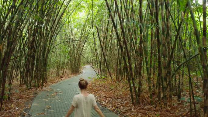 年轻女子伸开双臂在竹林中享受大自然的气息