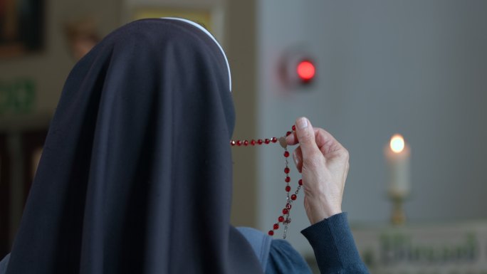 从一个持念珠祈祷的宗教修女的背后看。