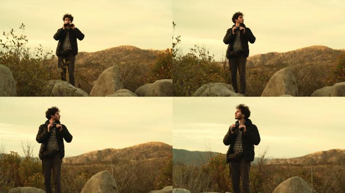 年轻人在山上用双筒望远镜观察大自然