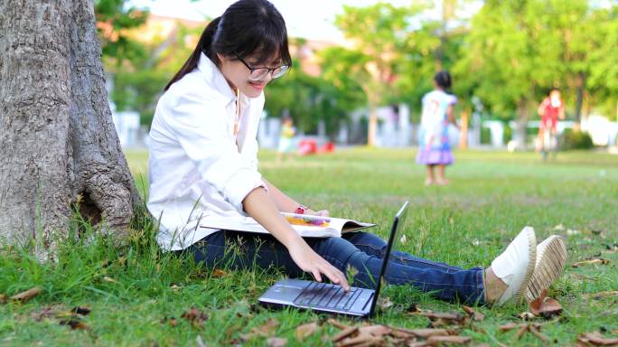 女孩在公园树下看书、用笔记本电脑打字