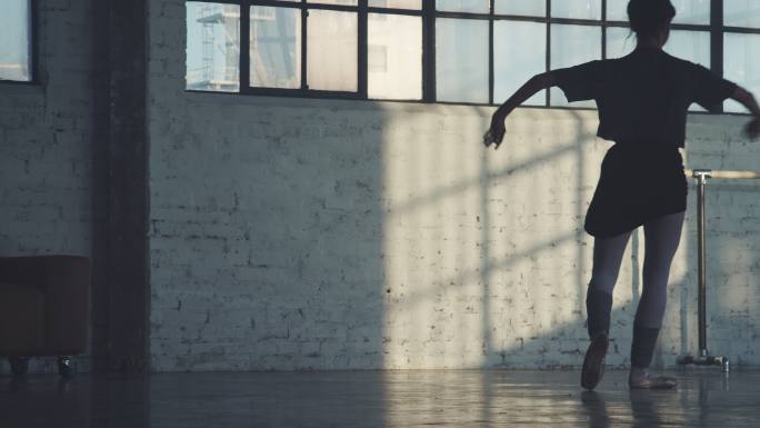 芭蕾舞演员在砖墙上旋转的影子