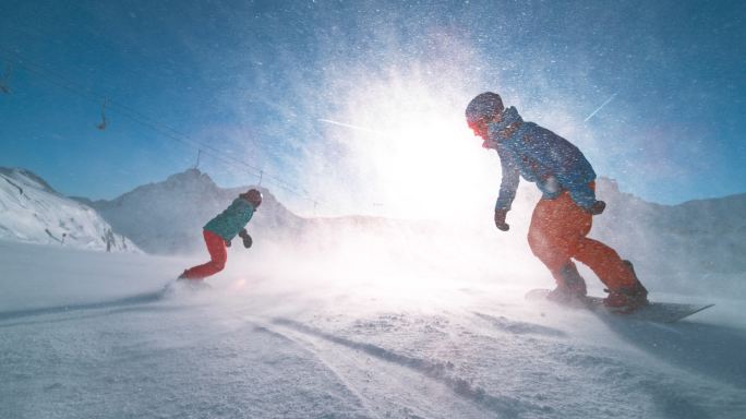 男女滑雪板运动员在阳光下滑雪
