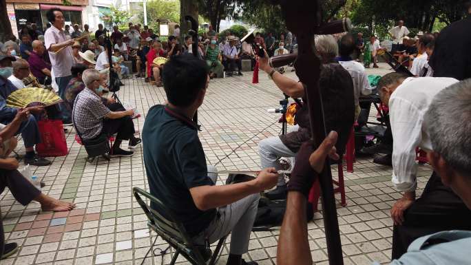 人民公园许多老人坐板凳听戏