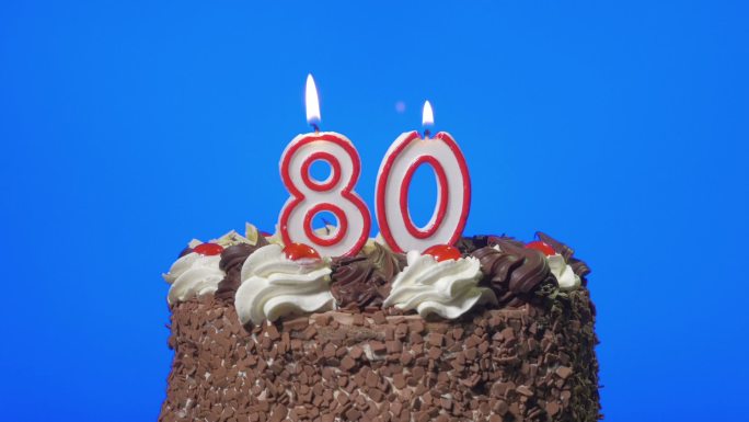 在美味的巧克力蛋糕上吹灭80岁的生日蜡烛