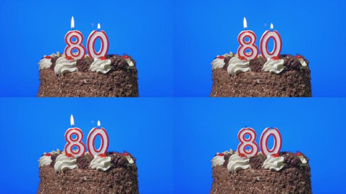 在美味的巧克力蛋糕上吹灭80岁的生日蜡烛