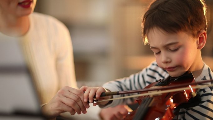 教小男孩拉小提琴的年轻女子
