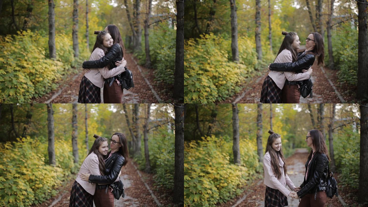 母亲和女儿在秋天公园散步，交谈和拥抱