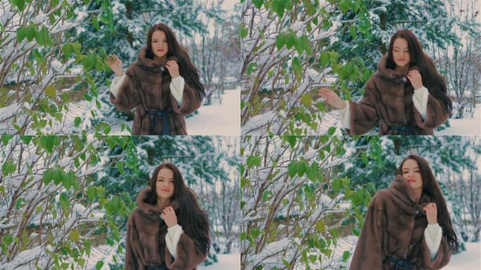 女孩在冬天靠近绿树，穿着棕色皮毛外套