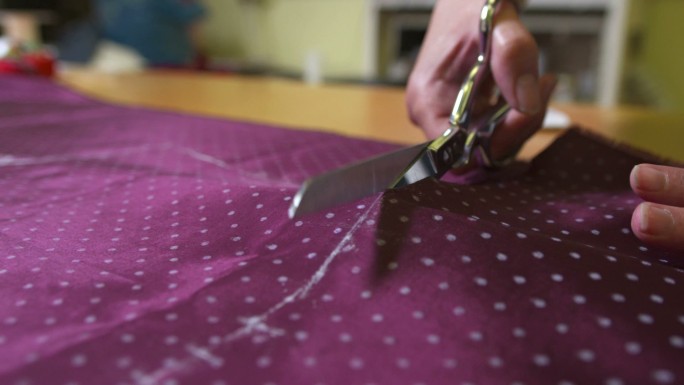 裁缝用大剪刀剪一块布料的特写镜头。