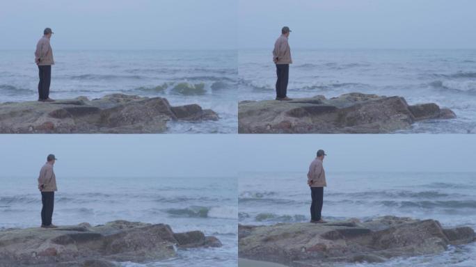 老人看海浪花拍打岩石
