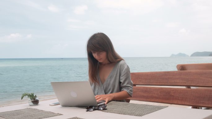 年轻女子在户外咖啡馆的笔记本电脑上工作
