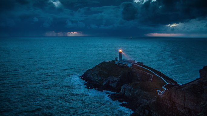 暴风雨海岸线上的带光束的灯塔