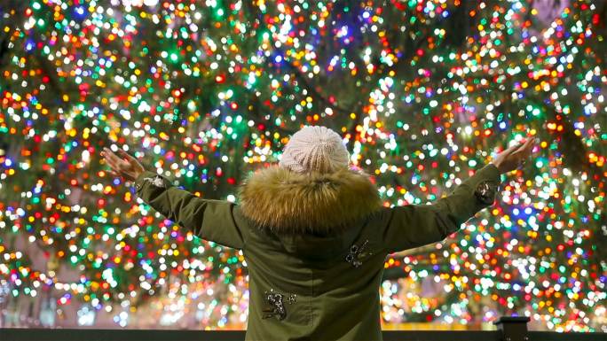 纽约洛克菲勒圣诞树背景上的快乐女孩。