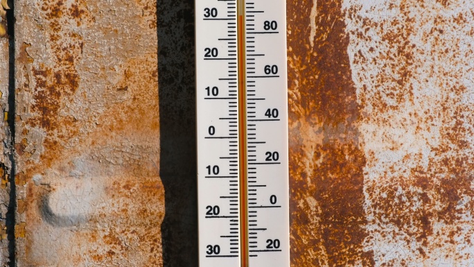 生锈墙上的温度计显示30度的温度