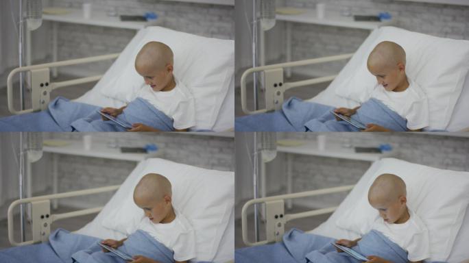 一个小男孩在病床上玩平板电脑