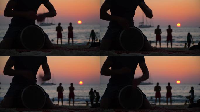 日落时分，一个男人在海滩上玩德杰姆贝鼓