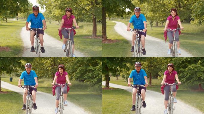 一对老年夫妇骑着自行车穿过公园