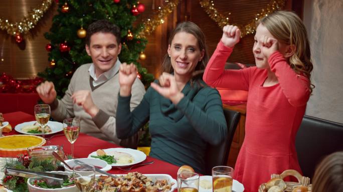一家人围坐在圣诞桌旁跳有趣的舞蹈