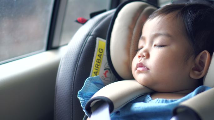 小孩坐在儿童车的座位上熟睡