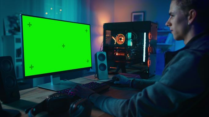 一个人坐在绿色屏幕电脑面前。