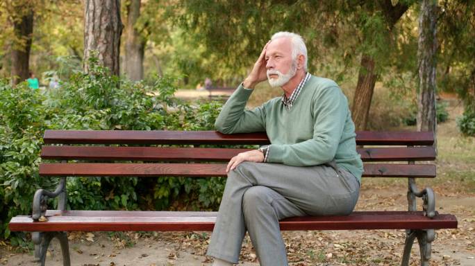 一个老人独自坐在公园的长椅上