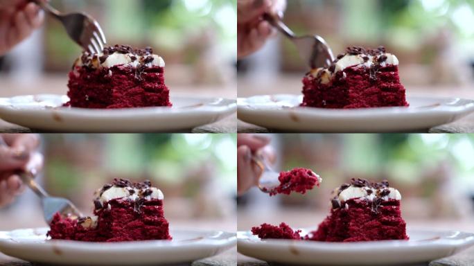 一个女人用叉子切一块红色天鹅绒蛋糕