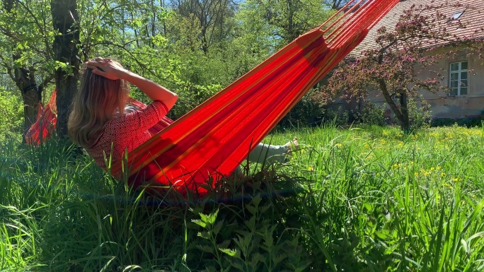 在一个美丽的夏日，年轻女子在吊床上放松