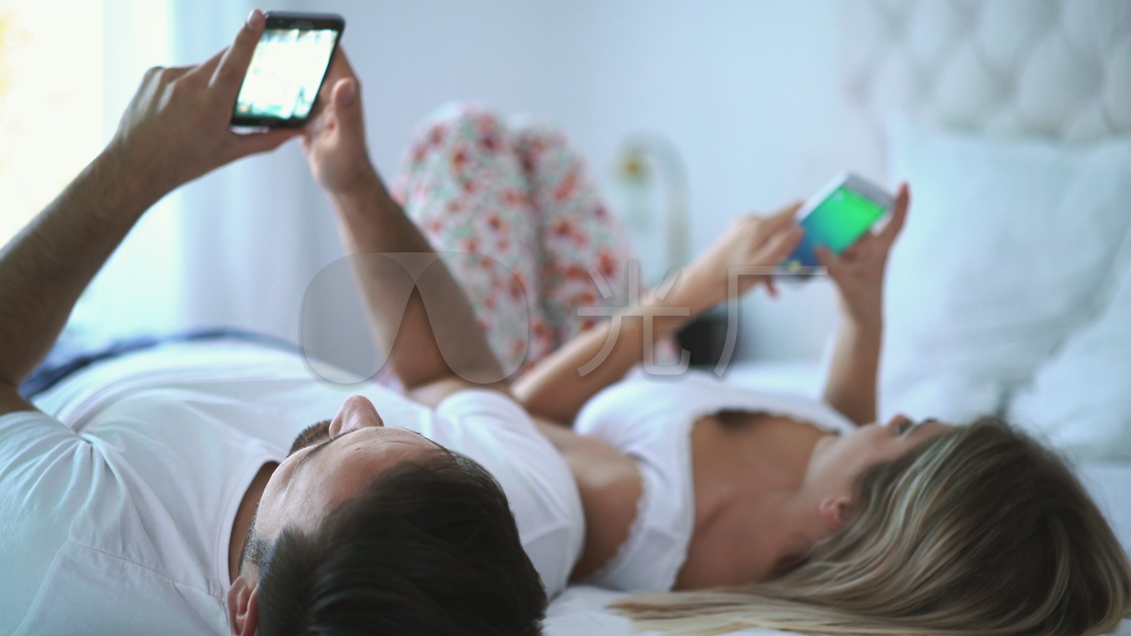 一对夫妇一起躺在床上玩手机