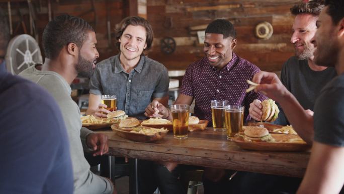 一群男性朋友在酒吧喝啤酒吃汉堡