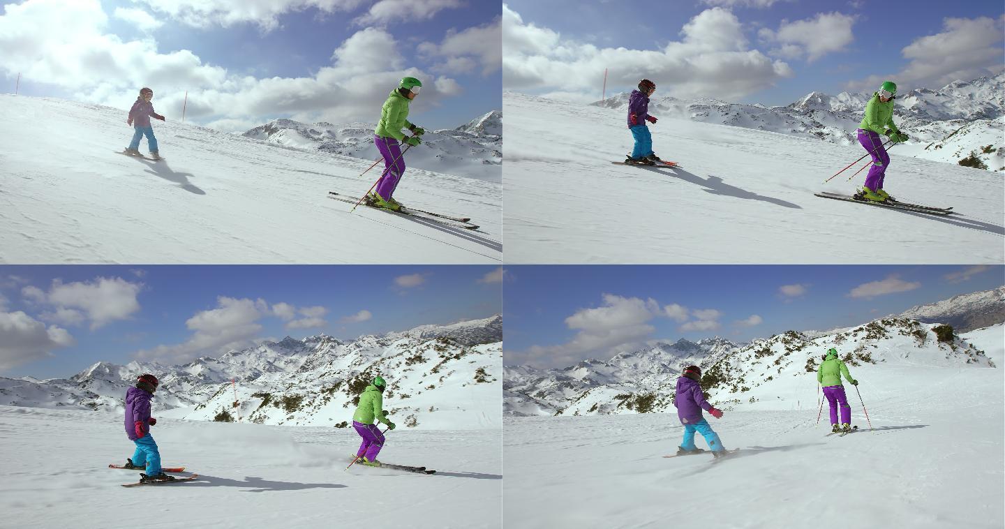小女孩在她的滑雪教练/母亲后面滑雪