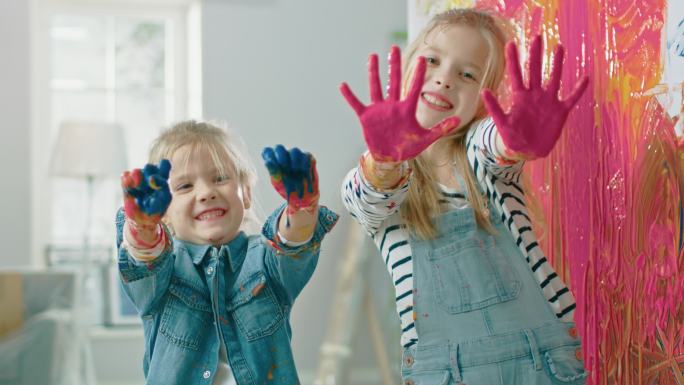 两个有趣的小妹妹展示了他们浸在彩色颜料里的手