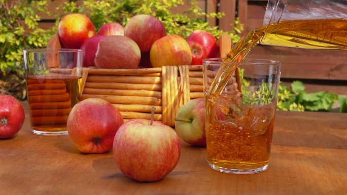 木桌上放着苹果汁和一篮熟苹果