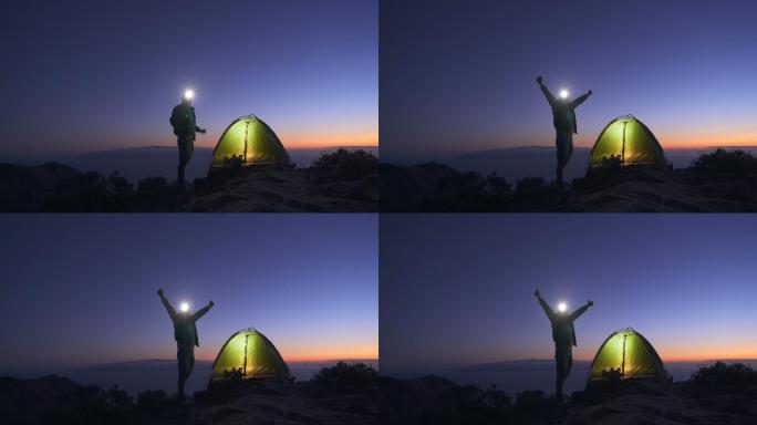 黄昏时分，快乐的游客在山顶搭起帐篷