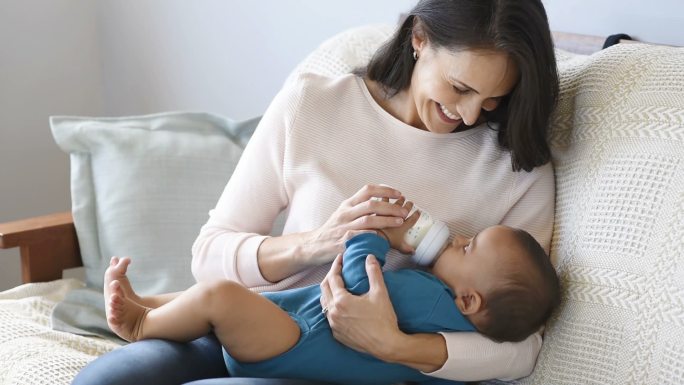 妈妈在给孩子喂奶抚摸护理儿童家庭深情女婴