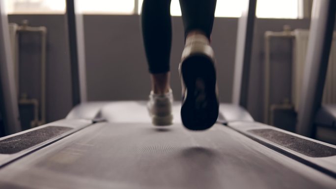 在跑步机上穿着运动鞋的女性腿部的慢镜头