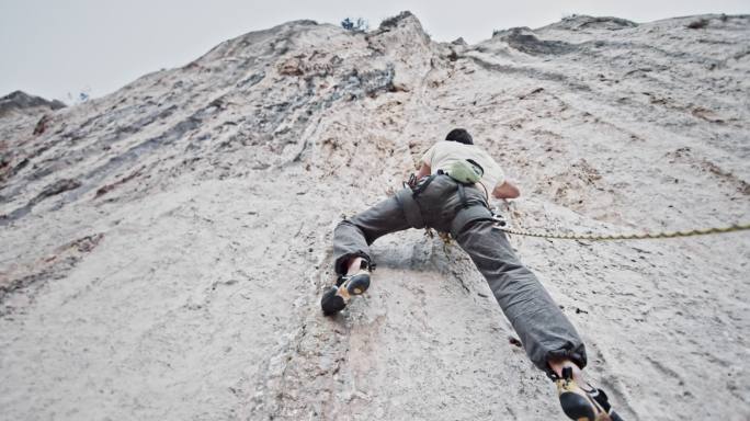 一名男性攀岩者登上一座垂直的白色悬崖